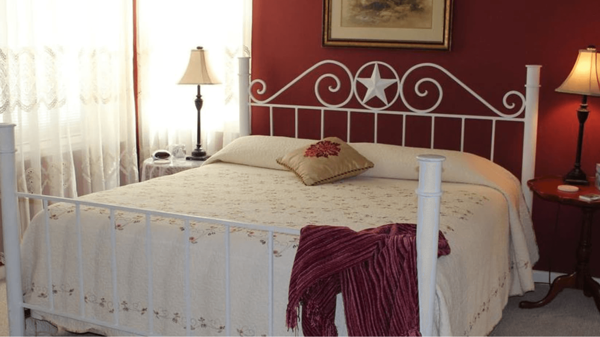 A cozy bedroom with a white metal bed, floral bedding, and warm lighting.